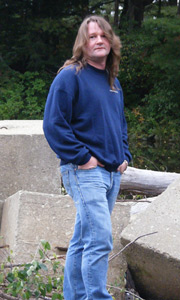 Picture of the author standing up in a wooded area